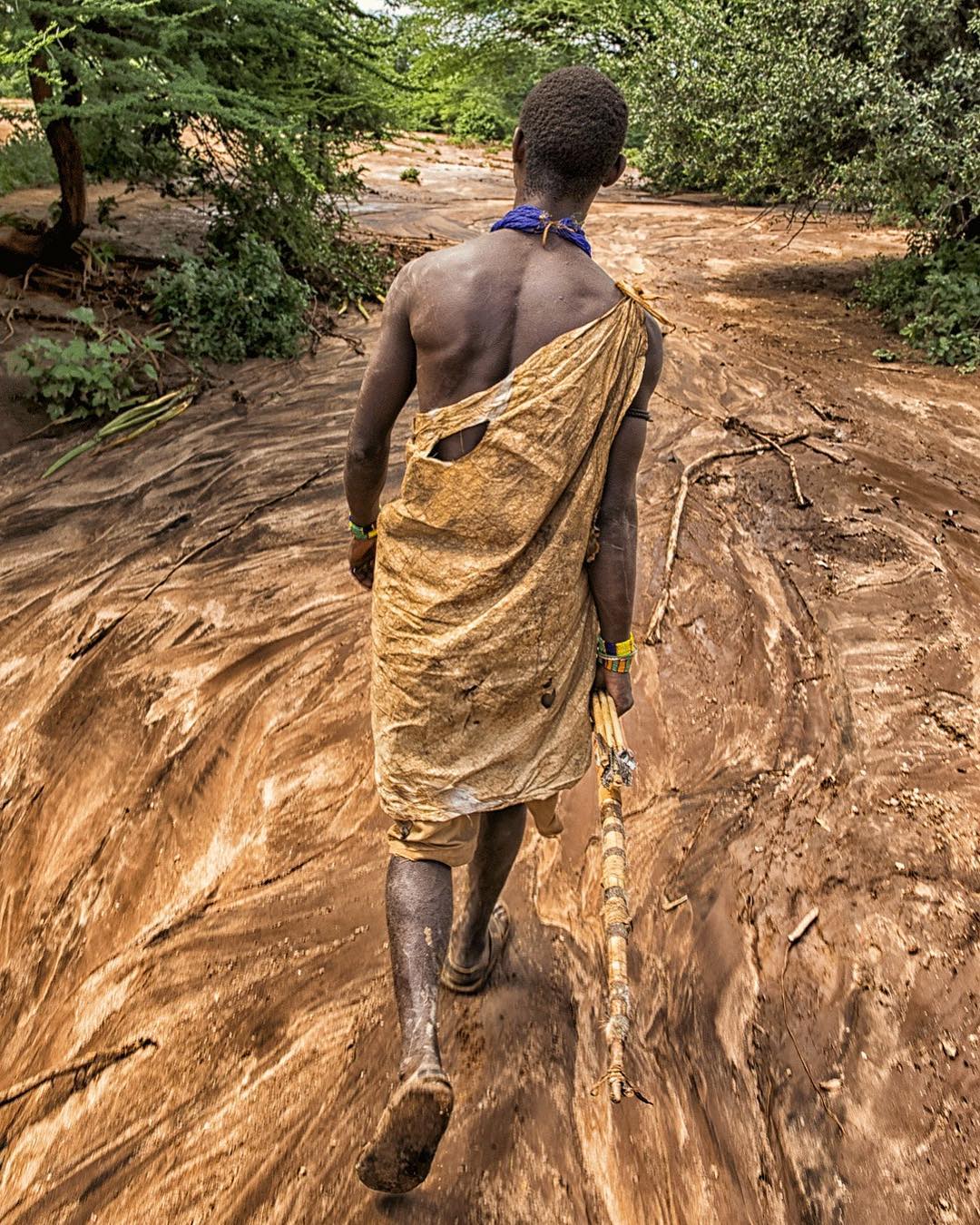 A Nadza tribesman walking through muddy African woods